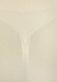 Beige ribbed tights with a smooth texture and subtle sheen. Features a reinforced center panel and seamless design for comfort.