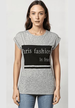 Camiseta gris de manga corta con un panel rectangular negro y texto blanco que dice "Moda de París en fran." Textura suave, corte relajado.