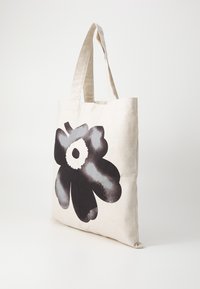 Canvas tote bag with long handles, featuring a large black and grey flower print on a natural beige background.