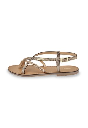 Sandali piatti con una parte superiore in pelle sintetica beige a motivo di serpente, caratterizzati da dettagli intrecciati e una fibbia dorata su una suola marrone chiaro.