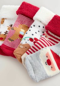 Set aus fünf bunten Socken mit festlichen Designs: flauschige rot-weiße Bündchen, Muster von Santa, Rentieren und Schneeflocken. Weicher Stoff.