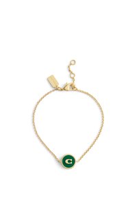 Gul kedjearmband med en cirkulär grön berlock med ett gyllene bokstav "C" i mitten. Justerbar lås med en tagg fäst.