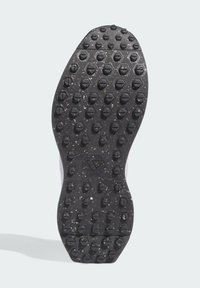 Black rubber shoe sole with a hexagonal pattern and circular studs, featuring a central textured area and white accents on the sides.