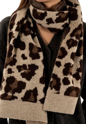 Écharpe beige avec un motif léopard en marron foncé et marron clair. Texture tricotée avec un ourlet côtelé. Portée par-dessus un cardigan gris foncé.