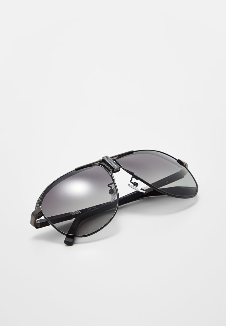 Czarne okulary aviator z gradientowymi szarymi soczewkami, metalicznymi akcentami i teksturowanym mostkiem. Lekka oprawka.