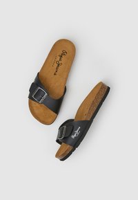 Svarta slidesandaler med en bred rem med en metallspänne, vadderad korksula och gummisula; upphöjd logotyp på innersulan.