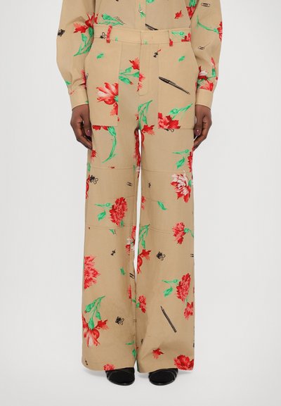 Pantalones de pierna ancha de tela tawny con patrones de flores rojas audaces y hojas verdes, con acentos gráficos negros dispersos.