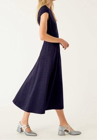 Mörkblå midiklänning i jersey med en kroppsnära överdel och vid kjol, kombinerad med grå klackskor med remdesign och fyrkantig tå.