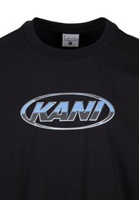 Black cotton t-shirt with a round neckline and a large silver oval logo that reads "KANI" in bold lettering across the chest.
