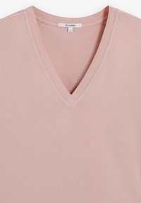 T-shirt z dekoltem w serek w miękkim różowym kolorze, z krótkim rękawem i subtelnymi detalami przeszyłkowymi. Lekki i gładki w dotyku.