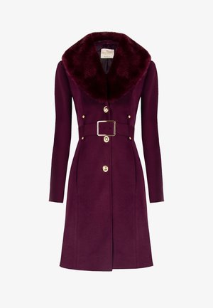 Burgunderroter Mantel mit Pelzkragen, figurbetonter Schnitt, langen Ärmeln und einem taillierten Gürtel. Mit goldenen Knöpfen und seitlichen Taschen.