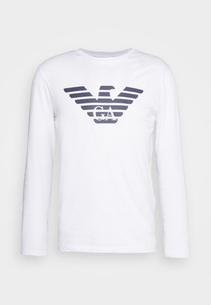 T-shirt à longues manches blanche avec un logo d'aigle rayé bleu marine et "GA" au centre. Fabriqué en coton doux et lisse.