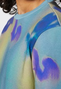 Felpa blu con un motivo a gradiente di vortici viola e verdi, realizzata in un tessuto morbido e testurizzato con un collo a costine.
