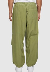Grønne, letvægtsbukser med elastisk talje, tapered manchetter og en baglomme. Glat tekstur, afslappet design, velegnet til forskellige anledninger.