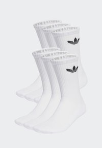 Baltas kokvilnas zeķes ar ribotām malām, ar melno Adidas logo un tekstu "THE 9 STRIPES" uz malas. Iepakojumā ir četri pāri.