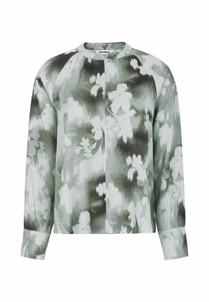 Lilleline pluus häguses rohelises ja valges, ümarate kaeluste, pikkade varrukate ja pehme, siledast tekstuurist, millel on vabalt langev lõige.