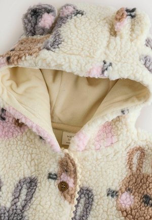 Haut à capuche en polaire couleur crème avec des motifs de lapins en beige, rose et gris. Doté d'une doublure douce, d'une fermeture à boutons et d'une capuche avec des oreilles.