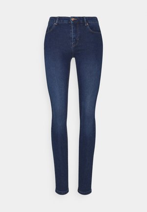 Jean skinny bleu foncé avec bouton et fermeture éclair à l'avant, passants de ceinture et poches avant standard, présenté sur un fond blanc uni.