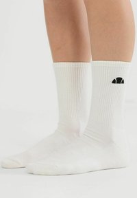 Calcetines de algodón blanco con textura acanalada y detalles de logotipo en negro, con un diseño de longitud media y una textura suave, aptos para uso casual.