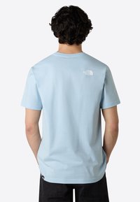 Camiseta de manga corta azul claro hecha de algodón. Presenta un pequeño logo blanco en la parte superior de la espalda y un corte relajado.