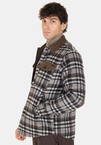 Giacca in flanella a quadri marrone e bianco con colletto in corduroy marrone, due tasche sul petto e una vestibilità comoda, che mette in mostra un tessuto testurizzato.