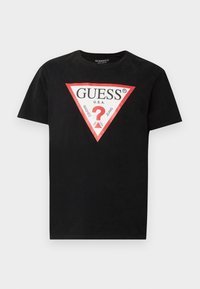 Cămașă de bumbac neagră cu un logo triunghiular roșu și alb, cu textul "GUESS U.S.A.". Guler rotund și mâneci scurte. Croială clasică.