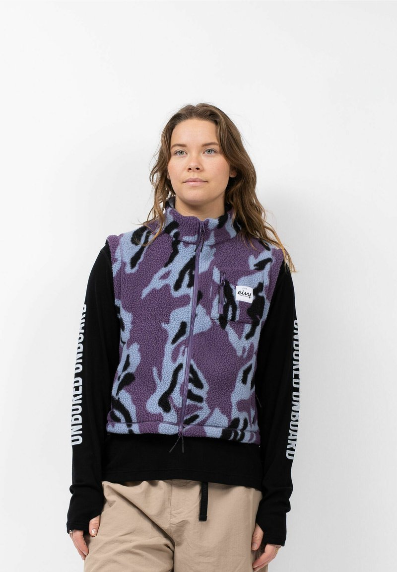 Paars en blauw gestippelde fleece vest met een hoge kraag, voorzak, ritssluiting en een zwart langslavend shirt eronder. Ontworpen met een comfortabele pasvorm.