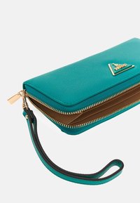 Teal wallet with textured exterior, gold zipper, and wrist strap. Features a triangular logo and brown interior with card slots.