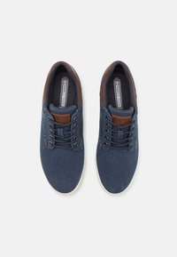 Blue denim sneakers with brown leather accents, lace-up closure, and a white rubber sole. Features a cushioned insole for comfort.