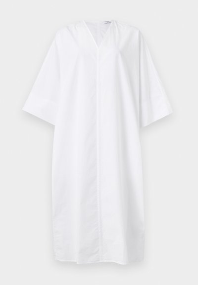 Χαλαρό λευκό φόρεμα μέχρι το γόνατο με φαρδιά μανίκια στα τρία τέταρτα και V-λαιμόκοψη, εμφανιζόμενο σε μονόχρωμο φόντο.