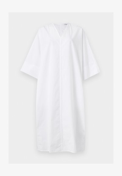 Χαλαρό λευκό φόρεμα μέχρι το γόνατο με φαρδιά μανίκια στα τρία τέταρτα και V-λαιμόκοψη, εμφανιζόμενο σε μονόχρωμο φόντο.