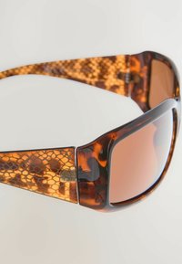 Gafas de sol carey con lentes marrones degradados, patillas texturizadas con un patrón de panal y un acabado brillante.