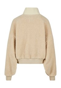 Giacca fluffy beige con una texture morbida, colletto alto e polsini a coste. Presenta un design cropped e orlo elastico per un look aderente.