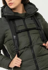 Giacca verde imbottita con cappuccio, dotata di zip frontale, texture trapuntata e cinture nere regolabili sulle spalle.