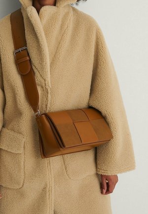 Braune Leder-Umhängetasche mit einem gesteppten Design, das eine glatte Textur und kontrastierende Paneele aufweist. Verstellbarer Riemen.