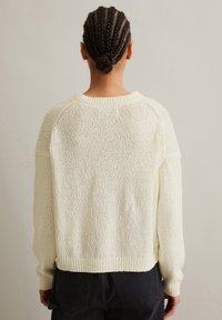 Strickpullover in Creme mit einem strukturierten Muster, Raglanärmeln und gerippten Bündchen. Abgerundet mit einem runden Ausschnitt und lockerer Passform.