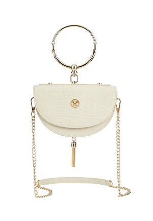 Bolso de mano color crema con forma de media luna, textura de cocodrilo, asa circular dorada, correa de cadena y detalle de borla dorada colgando debajo de la solapa.