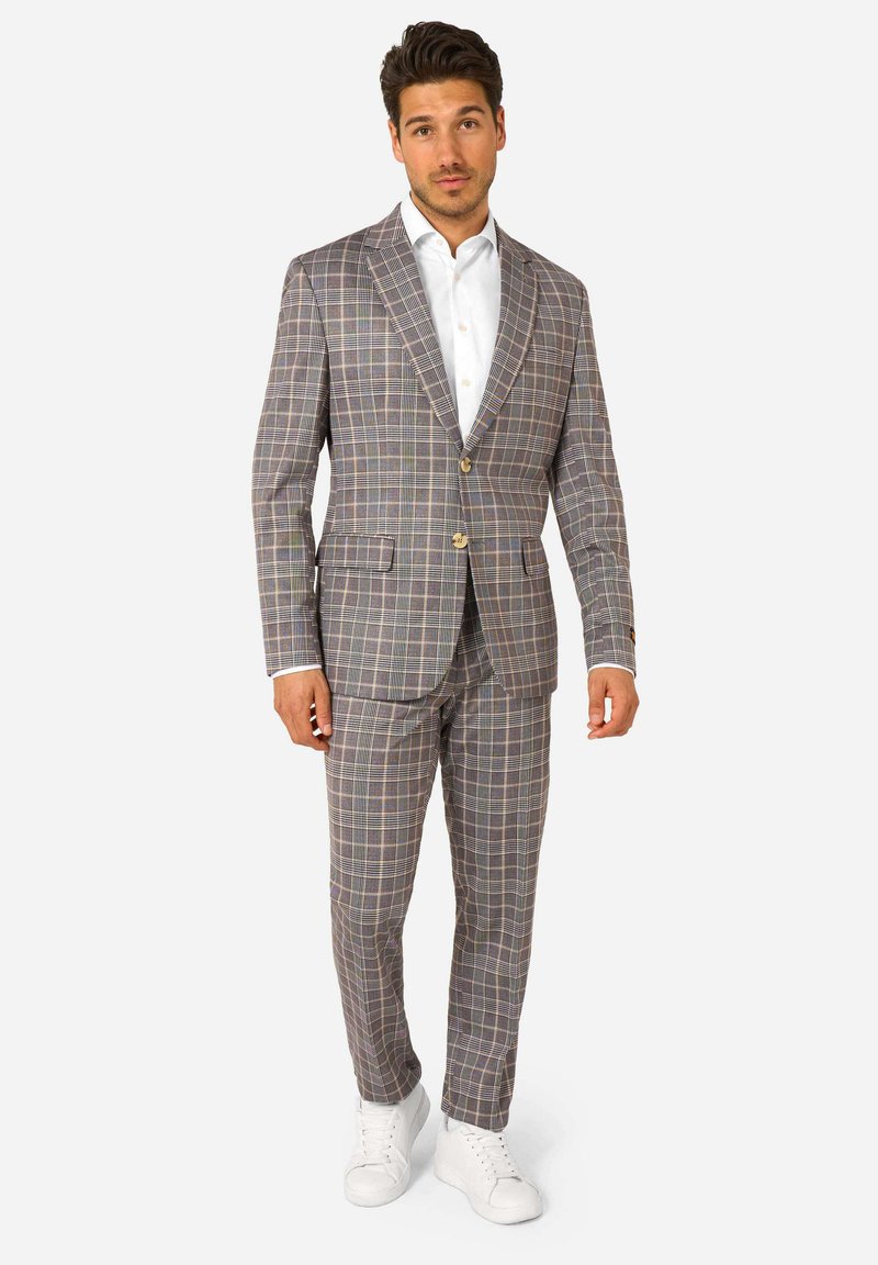 Traje de cuadros gris hecho de una tela ligera, que presenta una chaqueta ajustada con dos botones, pantalones a juego y zapatillas blancas.