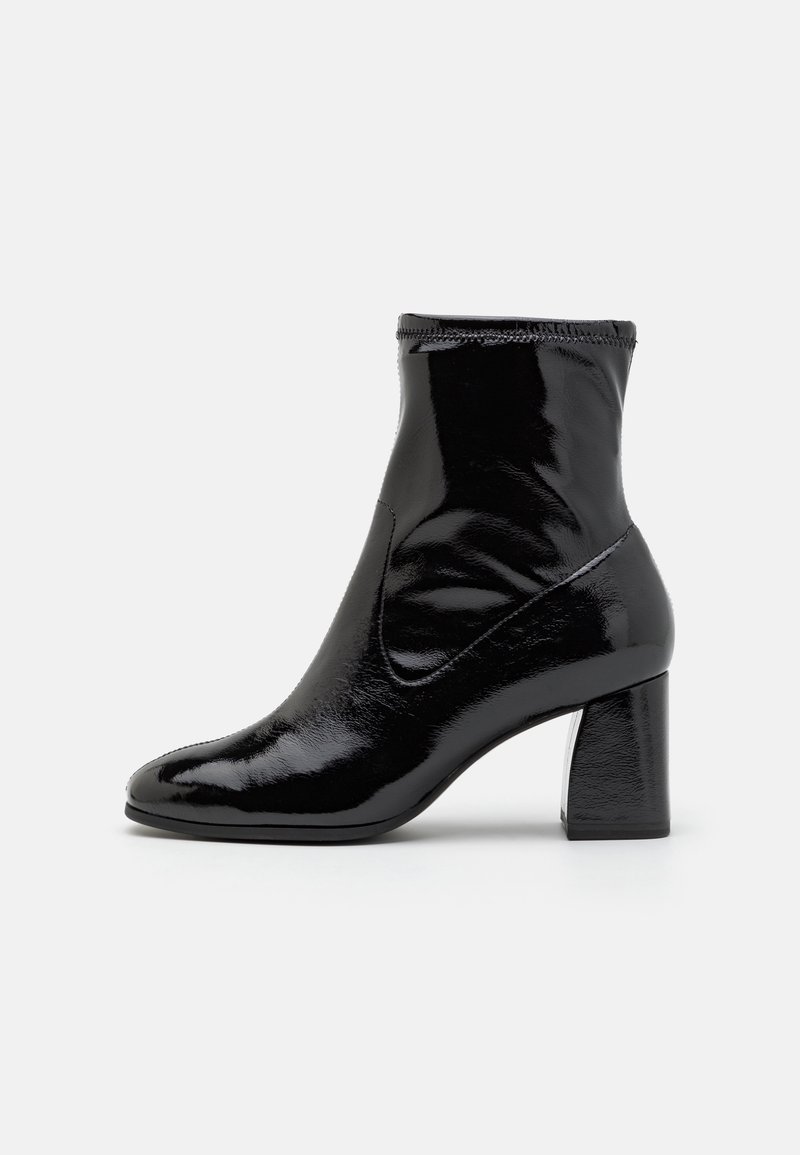 Bottine en cuir verni noir avec un talon haut épais, un design élégant, un bout arrondi et une tige élastiquée à la cheville.