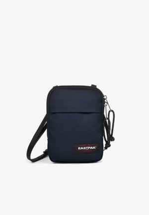 Compact navy blue crossbody bag with black adjustable strap, front zip pocket, and Eastpak logo patch at the bottom right corner.