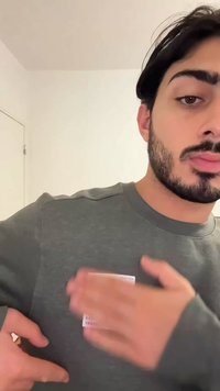 Maglione grigio con scollo rotondo e maniche lunghe, con etichetta bianca visibile sulla zona del petto. La trama appare morbida e casual.