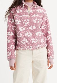 Fleece-Pullover, leicht, mit rosa-weißem Wolkenmuster, ausgestattet mit halbem Reißverschluss, hohem Kragen und Seitentaschen. Gerippte Bündchen.