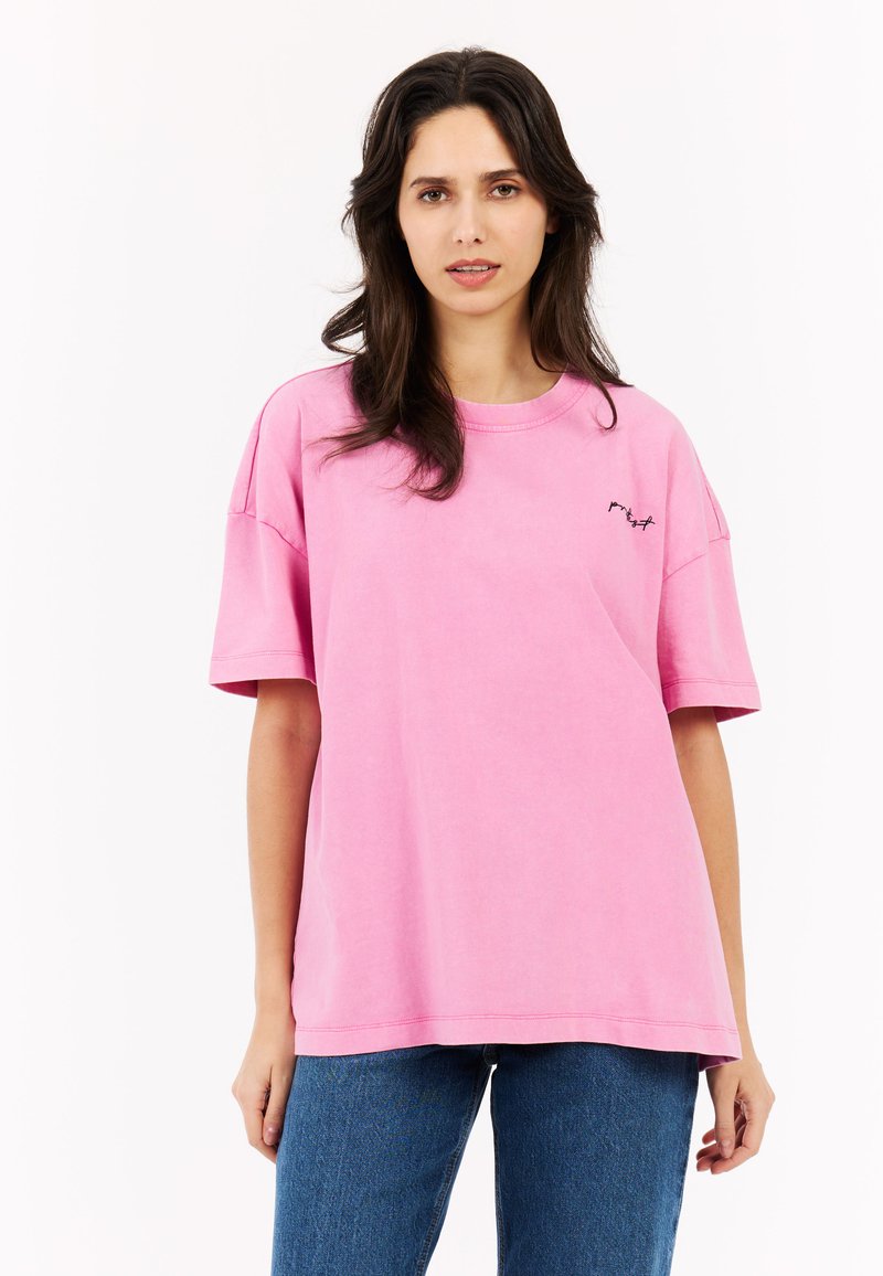 Roze katoenen t-shirt met korte mouwen, ronde hals en zwart geborduurd ontwerp op de borst. Draag het met blauwe denim jeans.