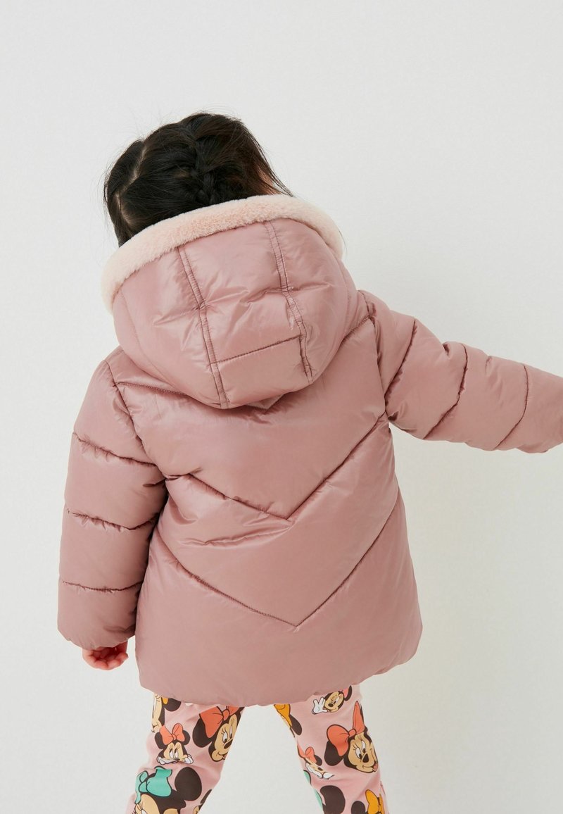 Pudret pink jakke med hætte, der har en blød faux fur krave og chevron syningsdesign. Bæret med mønstrede leggings.