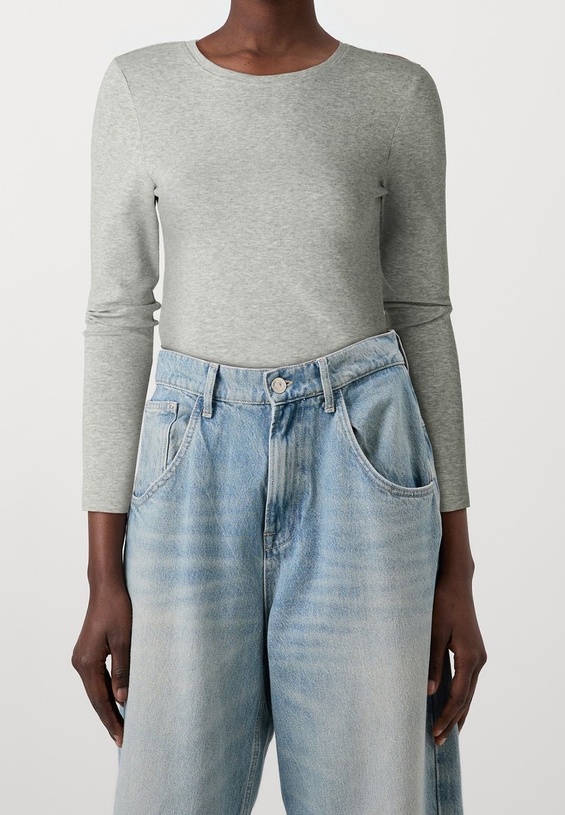 Helle graue Langarmshirt mit Rundhalsausschnitt, kombiniert mit lockeren, hellblauen Jeans aus Denim mit zwei Seitentaschen.
