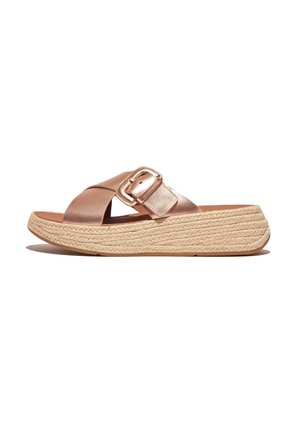 Sandales à glissière en or rose avec une large sangle croisée et une boucle métallique. Dispose d'une semelle en jute tressé pour un surcroît de hauteur.