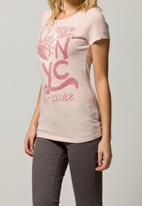 Světle růžové tričko z měkké bavlny, s odvážným grafickým potiskem sochy svobody a nápisem "NYC" v červené barvě. Krátké rukávy a slim fit design.