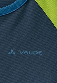 Jūras zils audums ar teksturētu virsmu, ar gaiši zilu "VAUDE" logo un zaļu akcentu gar vienu malu. Izstrādāts lietošanai ārā.