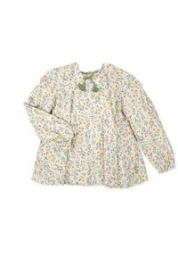 Blusa floral en tela color crema claro, con flores multicolores, mangas largas, hombros fruncidos y acentos de borlas verdes en el escote.