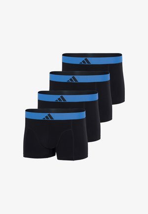 Männliches Model steht barfuß, trägt schwarze Boxer-Shorts mit einem blauen Bund und Adidas-Logo, schaut leicht nach rechts vor weißem Hintergrund.